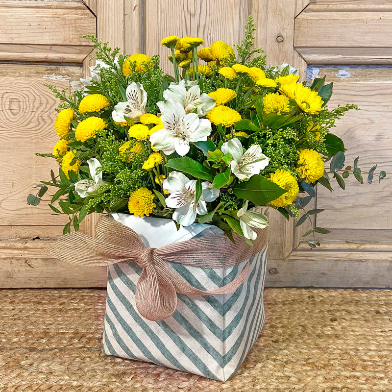 Cesta con margaritas amarillas y flores silvestres