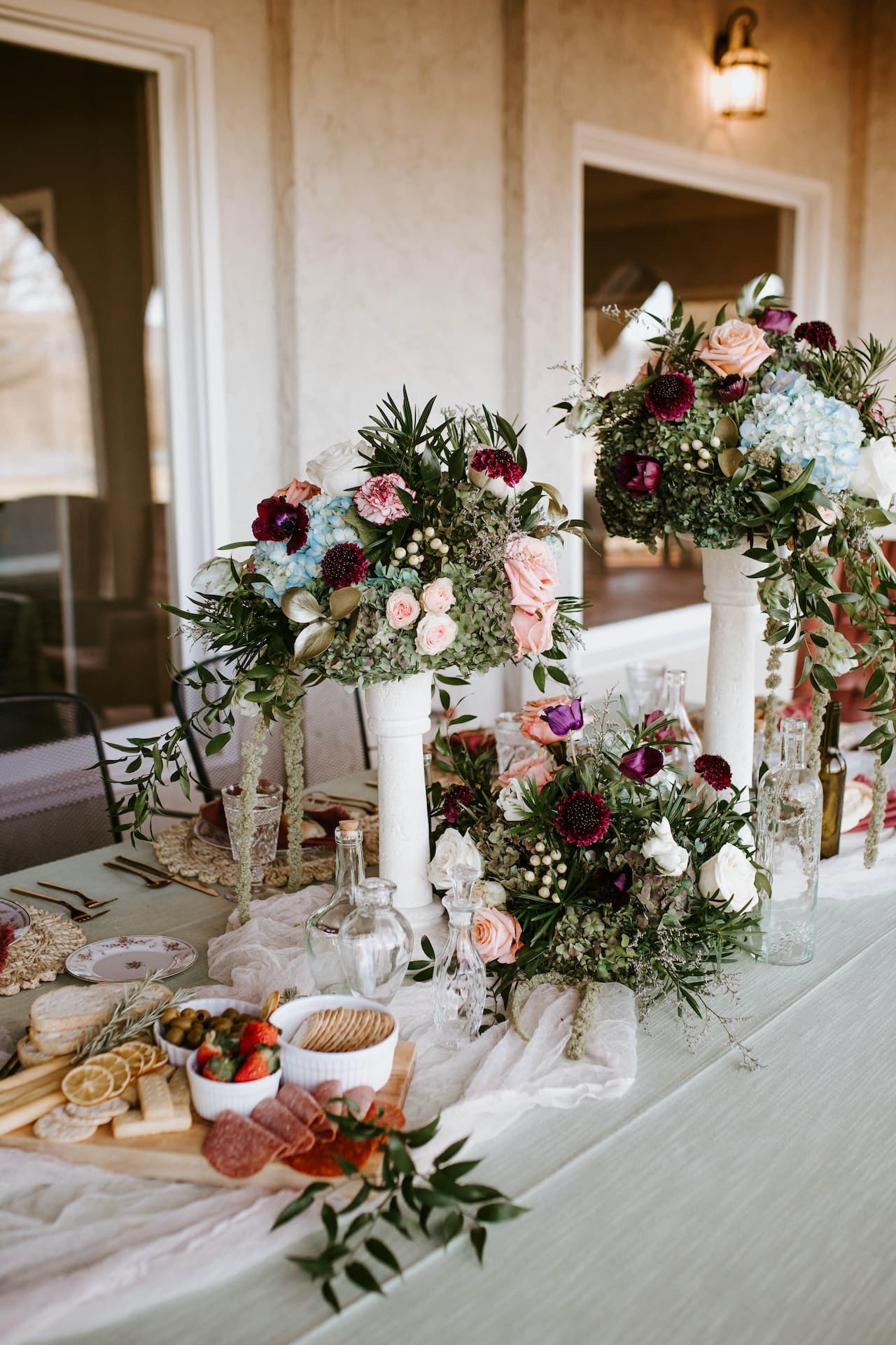 Mesa de evento con jarrones con flores y embutido para comer